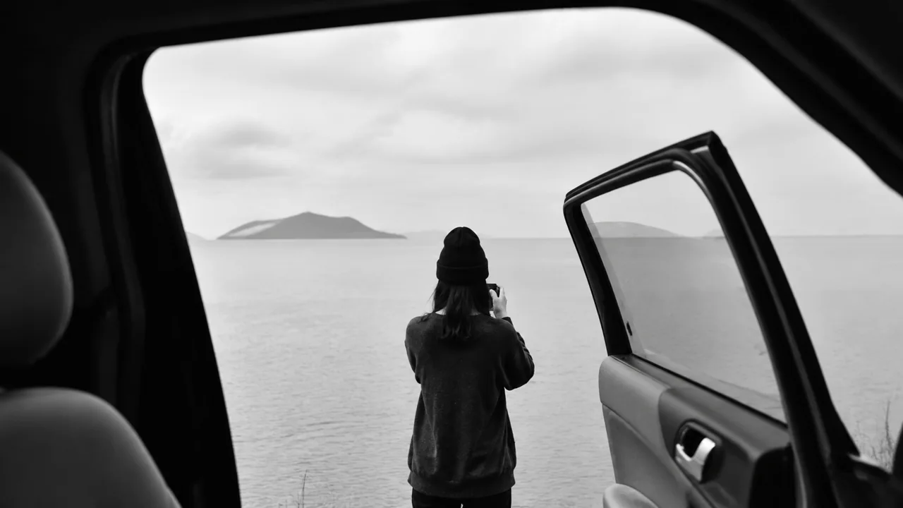 从车门望向海面的黑白旅行画面